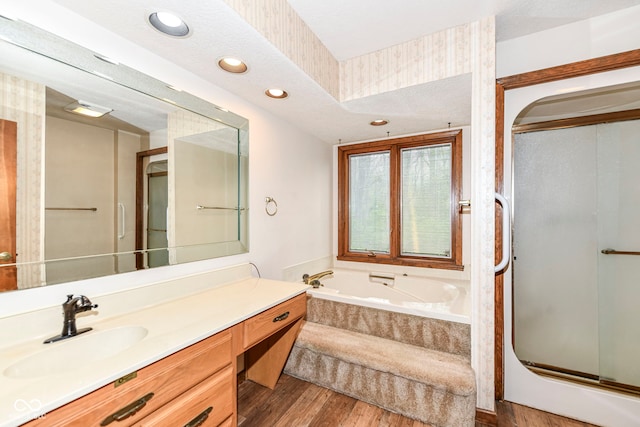 bathroom with recessed lighting, wood finished floors, vanity, a stall shower, and a garden tub