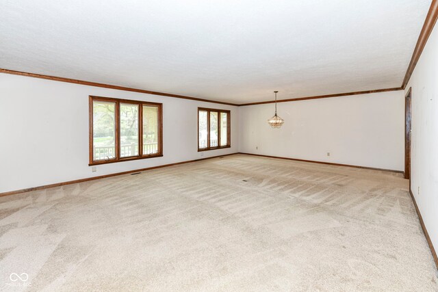 spare room with light colored carpet, crown molding, and baseboards