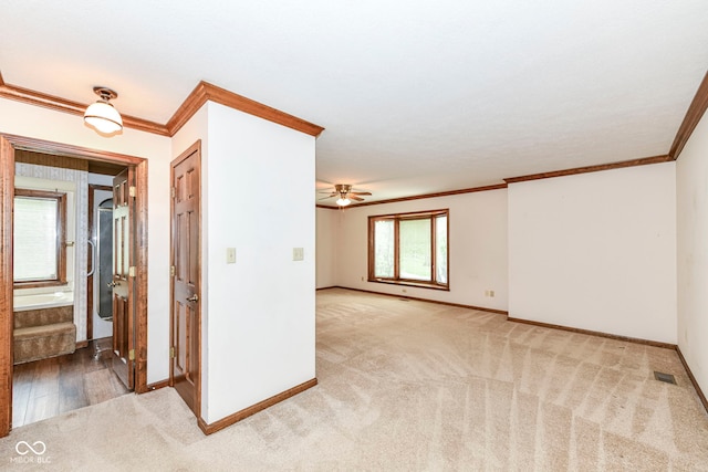carpeted empty room with ceiling fan, crown molding, visible vents, and baseboards