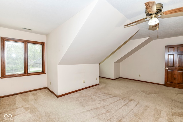 bonus room featuring ceiling fan, visible vents, vaulted ceiling, baseboards, and light colored carpet