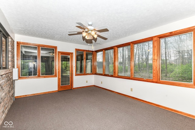 unfurnished sunroom with baseboards, a textured ceiling, and carpet