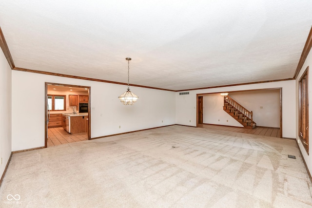 unfurnished living room featuring ornamental molding, visible vents, stairway, and light colored carpet
