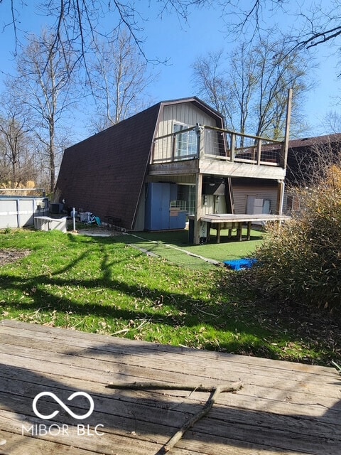 exterior space with a lawn, a gambrel roof, and a deck