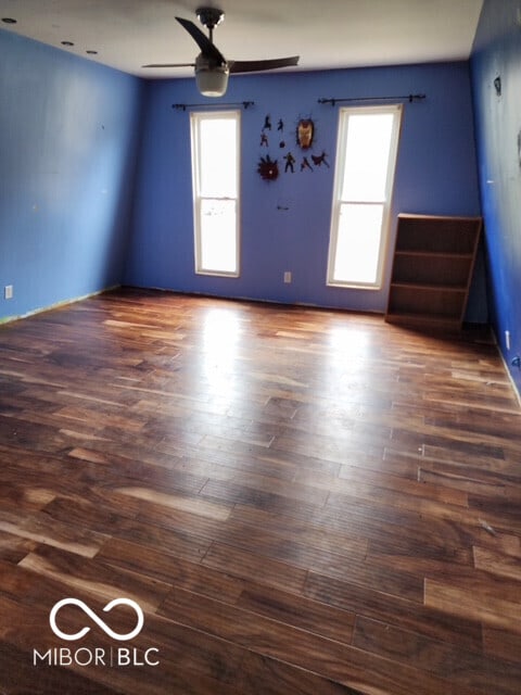 empty room featuring dark wood-style floors, ceiling fan, and a healthy amount of sunlight