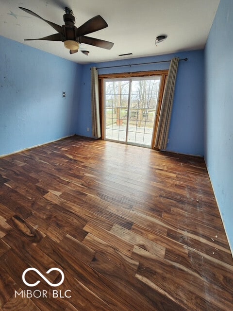 unfurnished room featuring visible vents, a ceiling fan, and dark wood-style floors