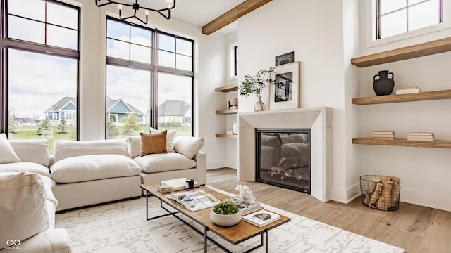 8082 Abington Way, Zionsville, IN 46077 - living room featuring wood finished floors, a glass covered fireplace, beamed ceiling, a high ceiling, and a notable chandelier
