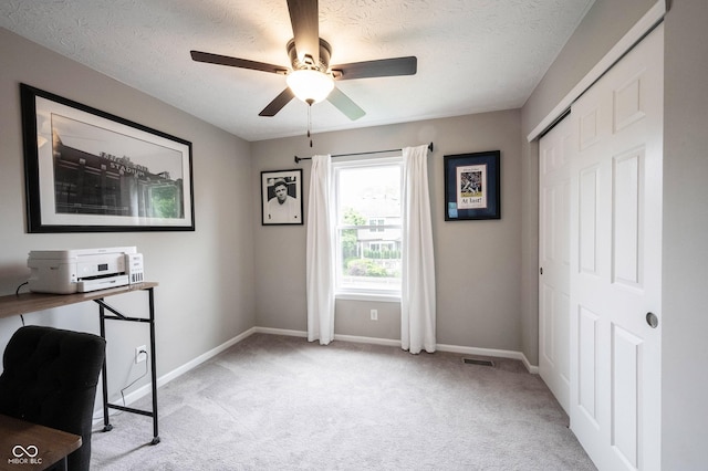 office area with light colored carpet, baseboards, ceiling fan, and a textured ceiling