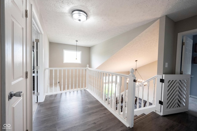corridor featuring dark wood-style flooring, a chandelier, and a textured ceiling