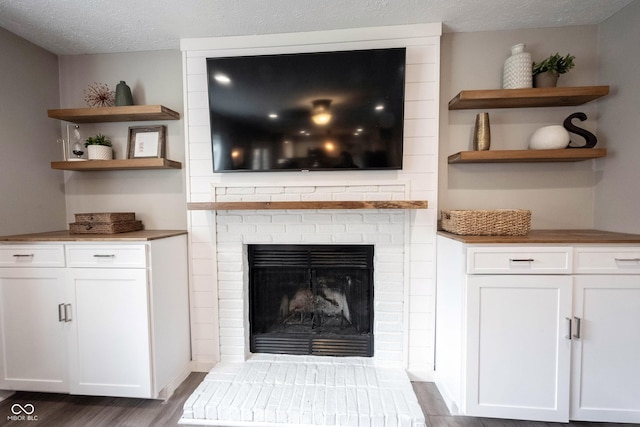 detailed view of wood finished floors, a fireplace, and a textured ceiling