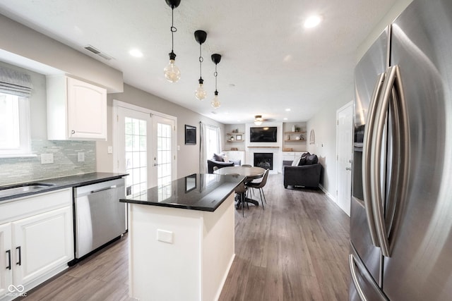 kitchen with appliances with stainless steel finishes, dark countertops, white cabinets, light wood-style flooring, and recessed lighting