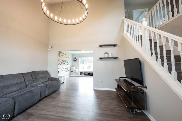 living room featuring a high ceiling, wood finished floors, a chandelier, baseboards, and stairs
