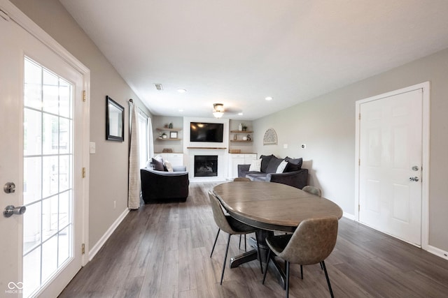 dining space with a fireplace, wood finished floors, baseboards, and recessed lighting