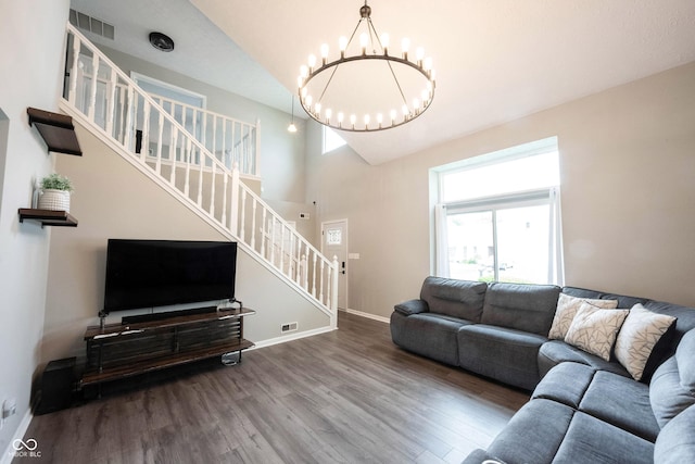 living area featuring stairway, wood finished floors, a chandelier, baseboards, and high vaulted ceiling