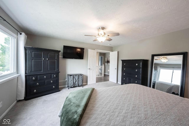 bedroom with baseboards, light colored carpet, ceiling fan, and a textured ceiling