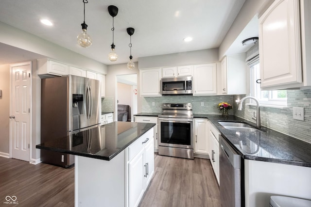 kitchen featuring appliances with stainless steel finishes, a sink, wood finished floors, white cabinetry, and recessed lighting