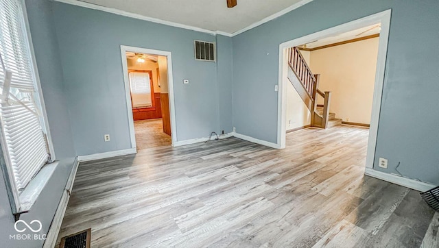 unfurnished room featuring stairs, wood finished floors, baseboards, ornamental molding, and visible vents