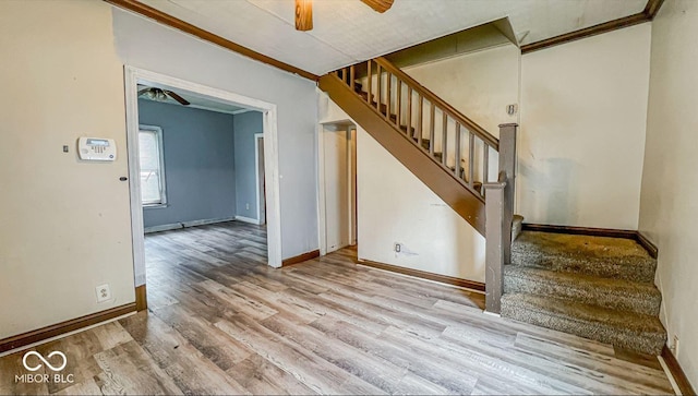 stairs with wood finished floors, a ceiling fan, baseboards, and ornamental molding