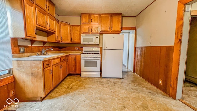 kitchen with brown cabinets, light countertops, a sink, white appliances, and stone finish flooring