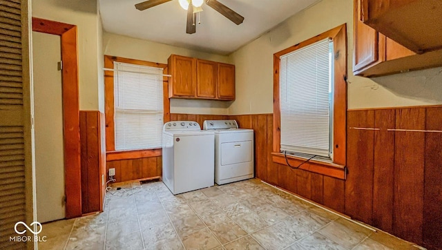 clothes washing area featuring washer and clothes dryer, wooden walls, ceiling fan, cabinet space, and a wainscoted wall