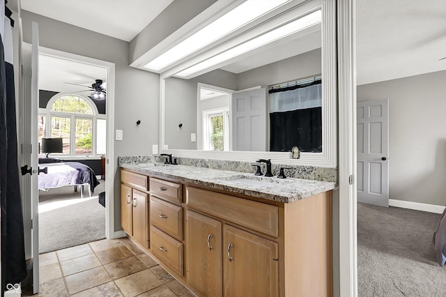 full bath featuring baseboards, double vanity, ceiling fan, and a sink