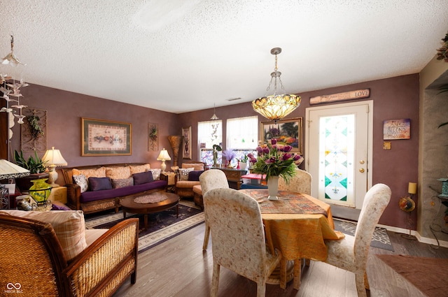 dining room featuring baseboards, a textured ceiling, wood finished floors, and a chandelier