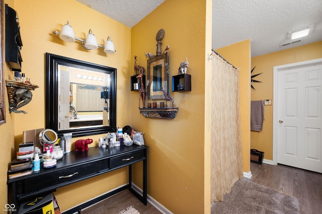 bathroom with vanity, visible vents, a textured ceiling, and wood finished floors