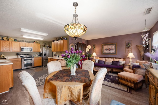 dining room featuring dark wood-style flooring, a notable chandelier, and visible vents