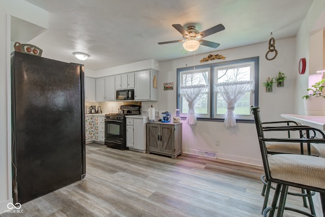 kitchen with a ceiling fan, black appliances, light wood-style floors, light countertops, and baseboards