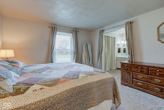 bedroom with ensuite bath and light carpet