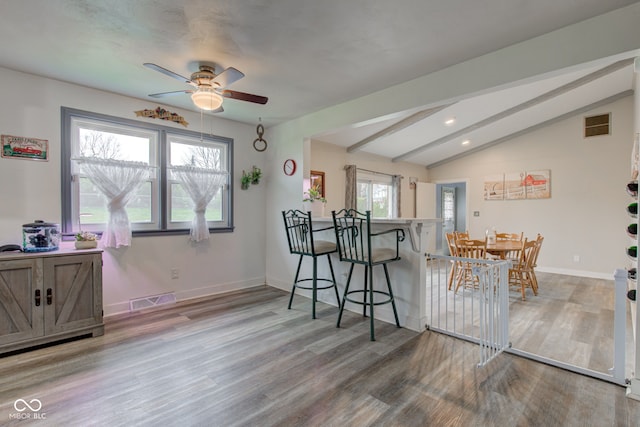 dining space with a ceiling fan, wood finished floors, lofted ceiling with beams, baseboards, and visible vents