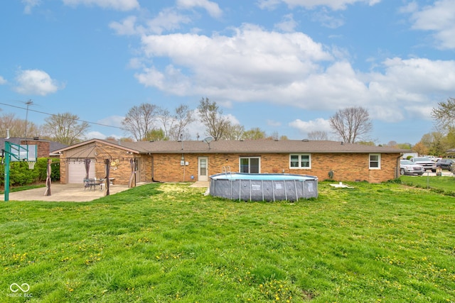 back of property featuring a lawn, brick siding, an outdoor pool, and a patio