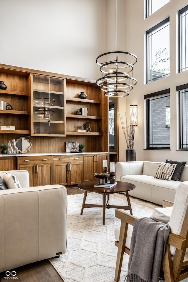 living room featuring a towering ceiling, wood finished floors, and a chandelier