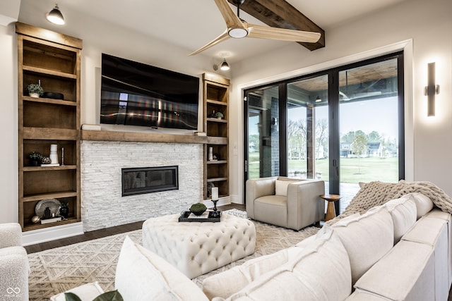living area featuring built in features, a stone fireplace, and wood finished floors