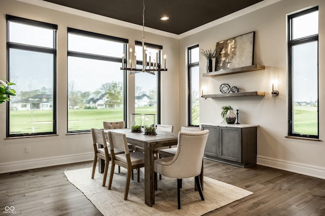 dining room featuring an inviting chandelier, baseboards, crown molding, and dark wood finished floors