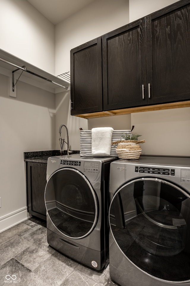 washroom featuring baseboards, washing machine and dryer, and cabinet space