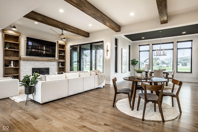 living area with baseboards, a healthy amount of sunlight, and light wood-type flooring