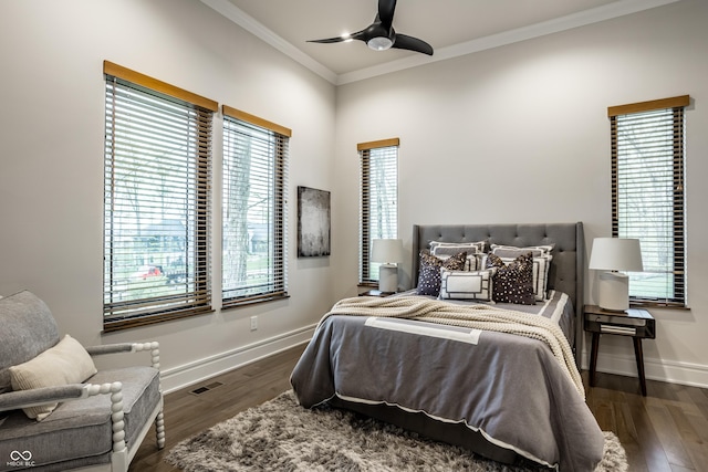 bedroom featuring visible vents, ornamental molding, wood finished floors, baseboards, and a ceiling fan