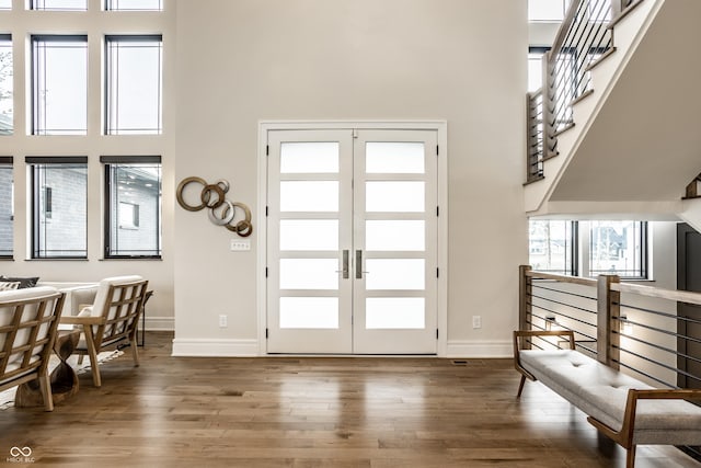 entryway featuring baseboards, wood finished floors, and a towering ceiling