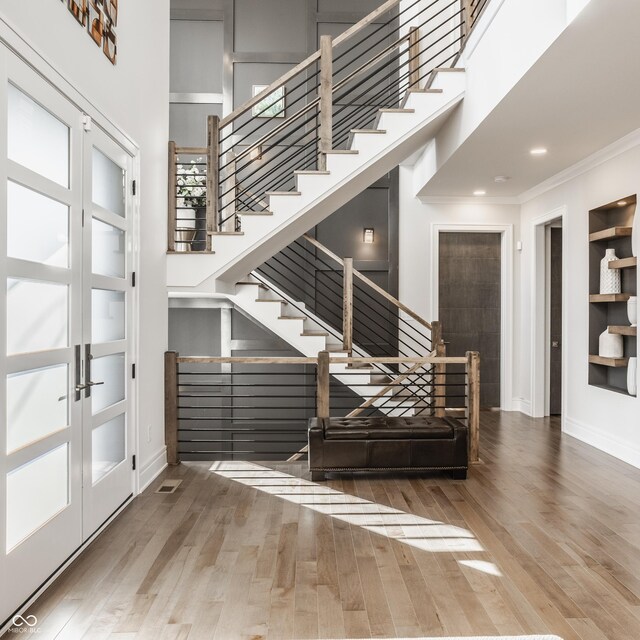 entryway with crown molding, wood finished floors, baseboards, a high ceiling, and french doors