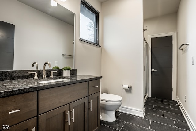 bathroom with vanity, baseboards, a shower stall, and toilet