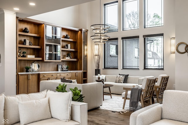 living area with recessed lighting, a high ceiling, an inviting chandelier, and wood finished floors