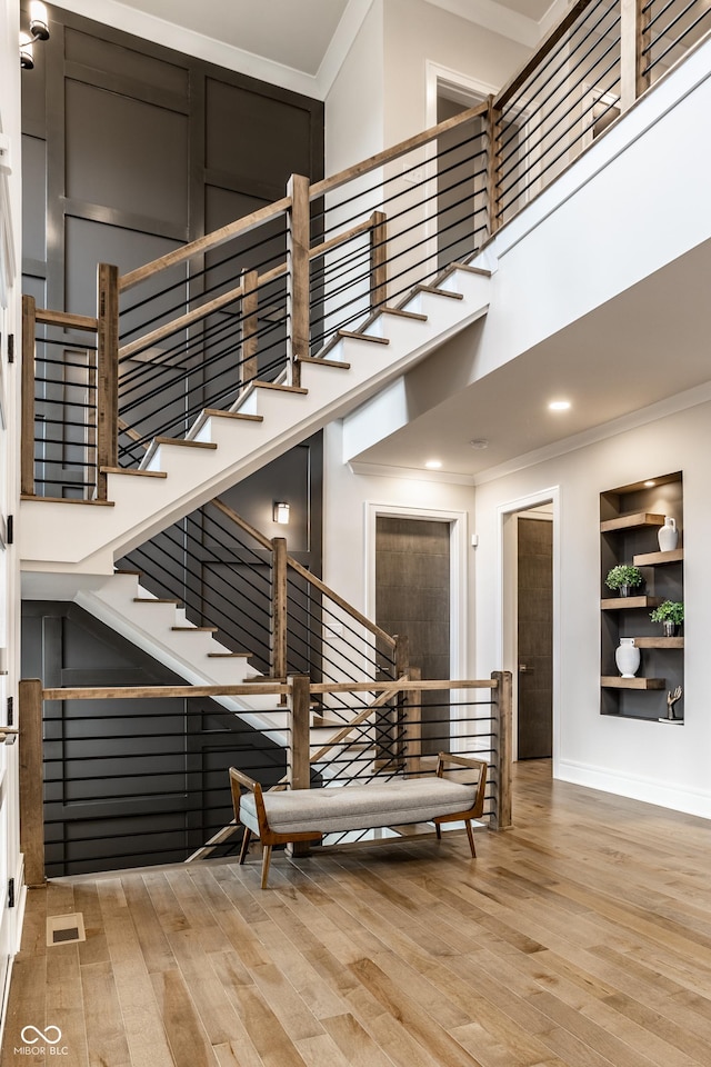 stairway with crown molding, built in features, and wood finished floors