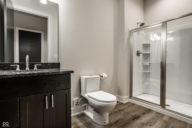bathroom with a shower stall, wood finished floors, vanity, baseboards, and toilet