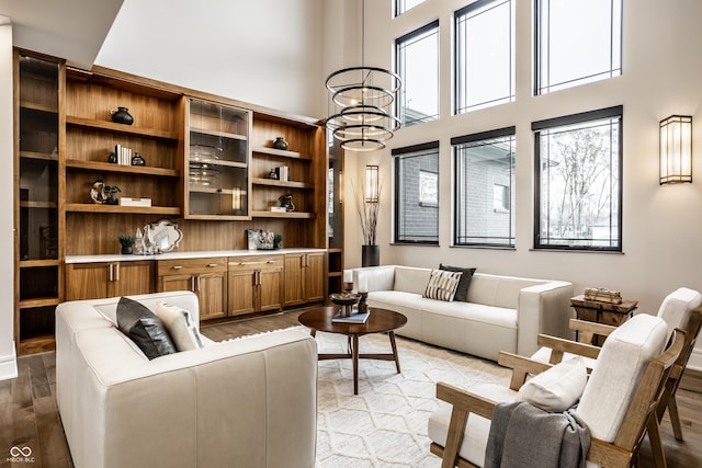 living area with a towering ceiling, wood finished floors, and a notable chandelier