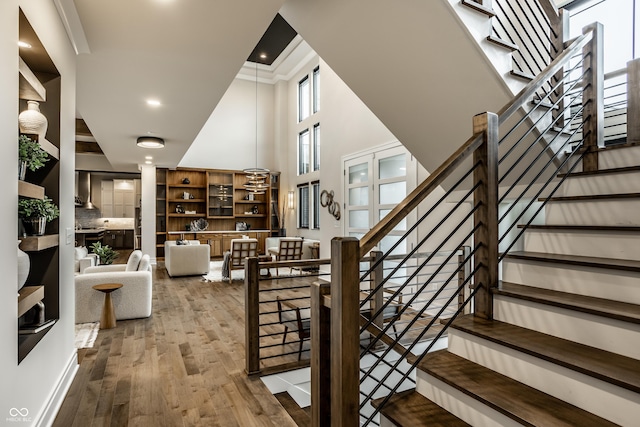 stairway with recessed lighting, a high ceiling, and wood finished floors