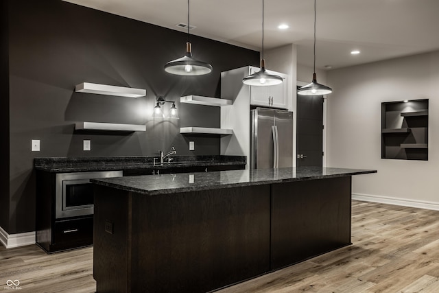 kitchen with freestanding refrigerator, oven, baseboards, light wood-type flooring, and a sink