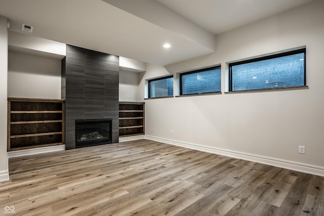 unfurnished living room with visible vents, a fireplace, wood finished floors, baseboards, and recessed lighting
