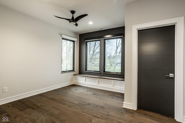 empty room with baseboards, a ceiling fan, dark wood finished floors, and visible vents