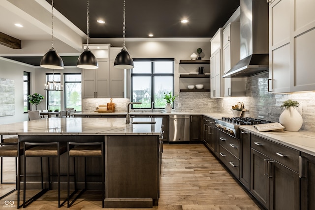 kitchen featuring light stone counters, plenty of natural light, wall chimney exhaust hood, and appliances with stainless steel finishes