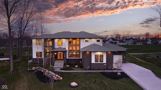 view of front of house with an attached garage, french doors, a yard, and driveway